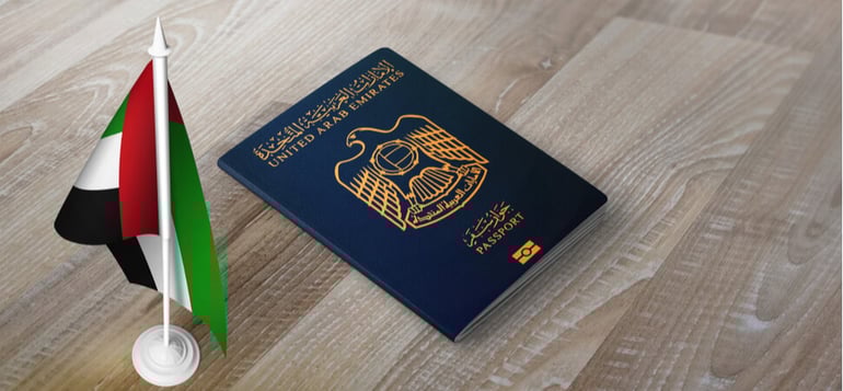 a UAE passport on a desk with an accompanying flag